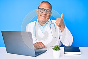 Senior handsome man with gray hair wearing doctor uniform working using computer laptop smiling with happy face looking and