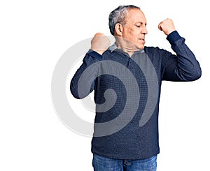 Senior handsome man wearing casual polo showing arms muscles smiling proud