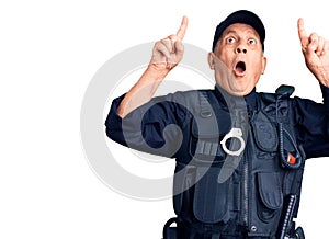 Senior handsome man wearing police uniform amazed and surprised looking up and pointing with fingers and raised arms