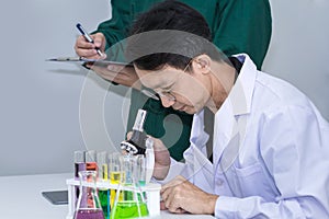 Senior handsome researcher with microscopes and color test tube.