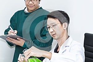 Senior handsome researcher with microscopes and color test tube.