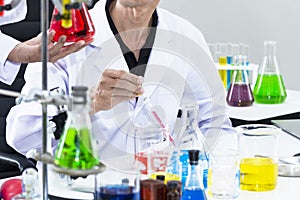 Senior handsome researcher mixing with color test tube.