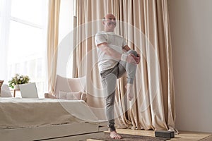 Senior handsome sportman doing stretching and balancing yoga exercise at home