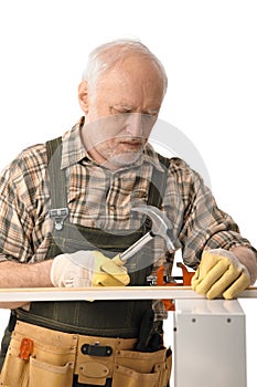 Senior handyman hammering