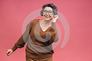 Senior happy aged business woman wearing glasses. Beautiful old woman, grandmother looking at camera and smiling. Isolated on pink