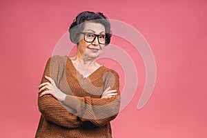 Senior happy aged business woman wearing glasses. Beautiful old woman, grandmother looking at camera and smiling. Isolated on pink