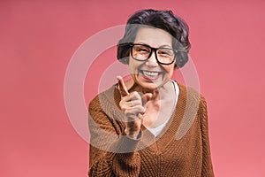 Senior happy aged business woman wearing glasses. Beautiful old woman, grandmother looking at camera and smiling. Isolated on pink