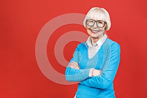 Senior happy aged businesswoman wearing glasses. Beautiful old woman looking at camera and smiling. Isolated on red background