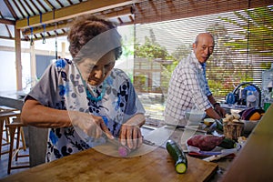 Senior happy and beautiful retired Asian Japanese couple cooking together at home kitchen enjoying preparing meal relaxed in aged