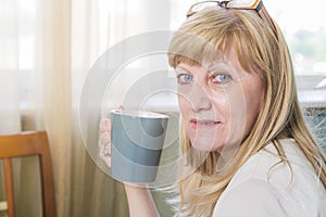 Senior happy blonde woman holding cup of coffee