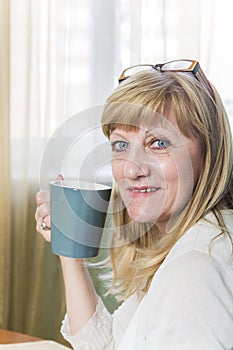 Senior happy blonde woman holding cup of coffee