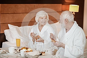 A senior happy couple enjoying breakfast while staying in bed