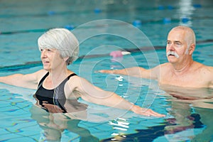 senior happy couple in swimming pool lesson