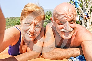 Senior happy couple taking selfie at beach resort in Thailand trip on tropical tour - Adventure and fun concept of active elderly