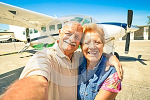 Senior happy couple taking selfie with private ultralight plane photo