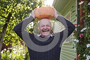 Senior happy hispanic man holding a pumpkin in hands.
