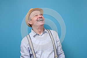 Senior happy man looking up smiling standing on blue background.