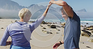 Senior hiker couple dancing on the beach while hiking.