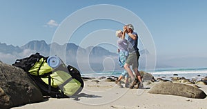 Senior hiker couple dancing on the beach while hiking.