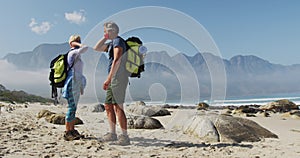 Senior hiker couple wearing face masks with backpacks greeting each other by touching elbows