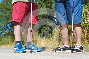 Senior hiker`s legs and hiking sticks close up