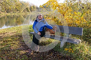 Senior hiker taking a break, sitting on wooden bench with her dog