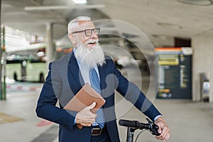 Senior hipster business man holding electric scooter while waiting at bus station - Focus on face