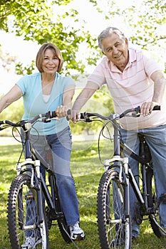 Senior Hispanic Couple Cycling In Park