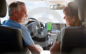 Senior Hispanic Couple On Drive Through Countryside Using Sat Nav On Mobile Phone