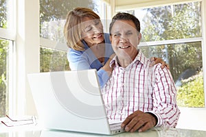 Senior Hispanic Couple In Home Office With Laptop