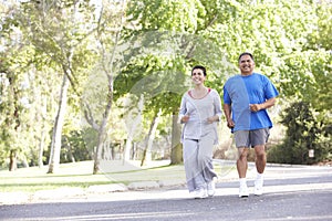 Senior Hispanic Couple Jogging In Park photo