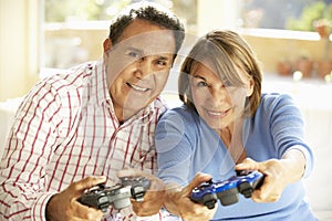 Senior Hispanic Couple Playing Video Game At Home