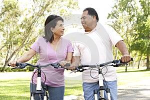 Senior Hispanic Couple Riding Bikes In Park