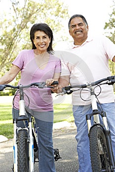 Senior Hispanic Couple Riding Bikes In Park