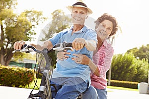 Senior Hispanic Couple Riding Bikes In Park