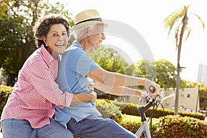 Senior Hispanic Couple Riding Bikes In Park