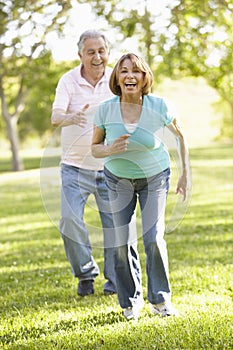 Senior Hispanic Couple Running In Park