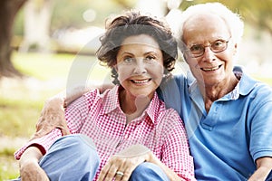 Senior Hispanic Couple Sitting In Park Together