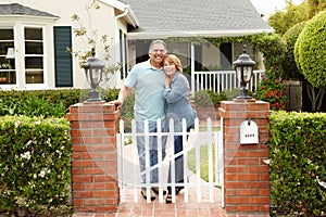 Senior Hispanic couple standing outside home photo