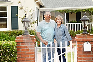 Senior Hispanic couple standing outside home