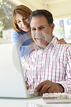 Senior Hispanic Couple Using Laptop In Home Office