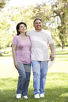 Senior Hispanic Couple Walking In Park