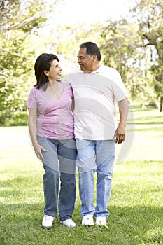 Senior Hispanic Couple Walking In Park