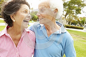 Senior Hispanic Couple Walking In Park Together