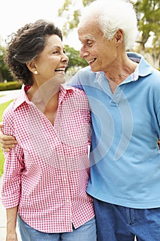 Senior Hispanic Couple Walking In Park Together