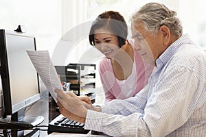 Senior Hispanic couple working on computer at home