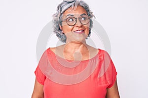 Senior hispanic grey- haired woman wearing casual clothes and glasses smiling looking to the side and staring away thinking