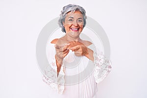 Senior hispanic grey- haired woman wearing casual clothes pointing fingers to camera with happy and funny face