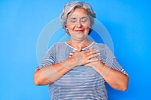 Senior hispanic grey- haired woman wearing casual clothes smiling with hands on chest with closed eyes and grateful gesture on
