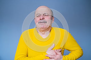 Senior hispanic man suffering from pain with heart attack.